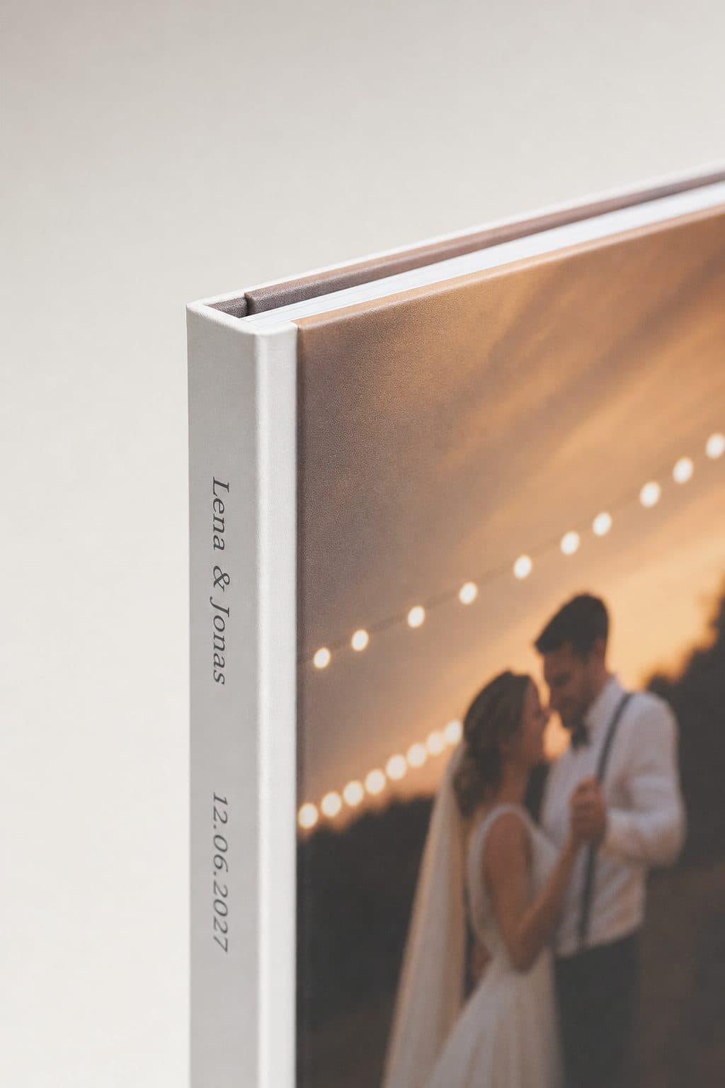 Nahaufnahme von Buchrücken und mattem Fotocover mit den Namen des Paares und dem Hochzeitsdatum